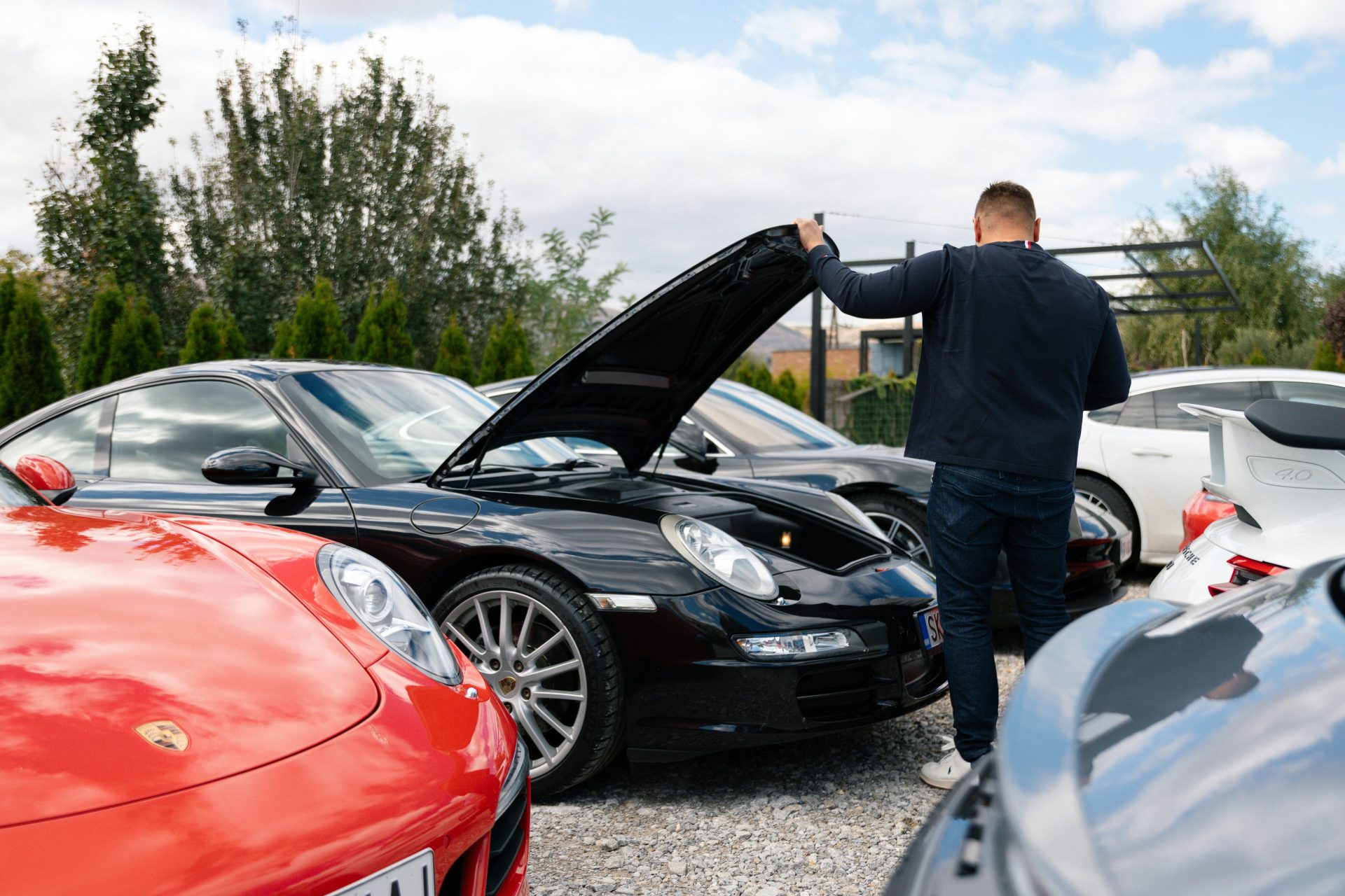 Mann öffnet Motorhaube eines schwarzen Sportwagens